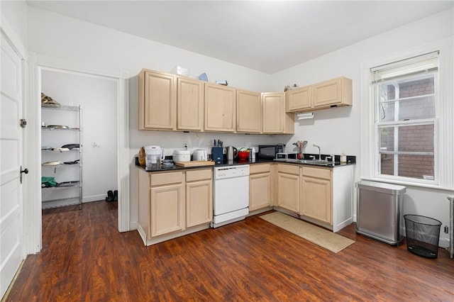 kitchen with dishwasher, dark countertops, dark wood-style flooring, light brown cabinetry, and a sink