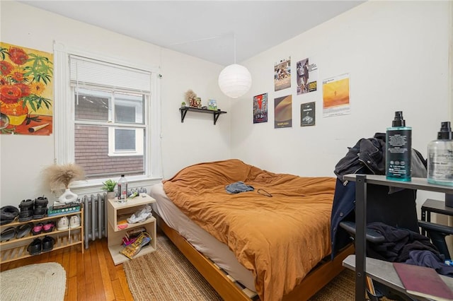 bedroom with radiator heating unit and hardwood / wood-style floors