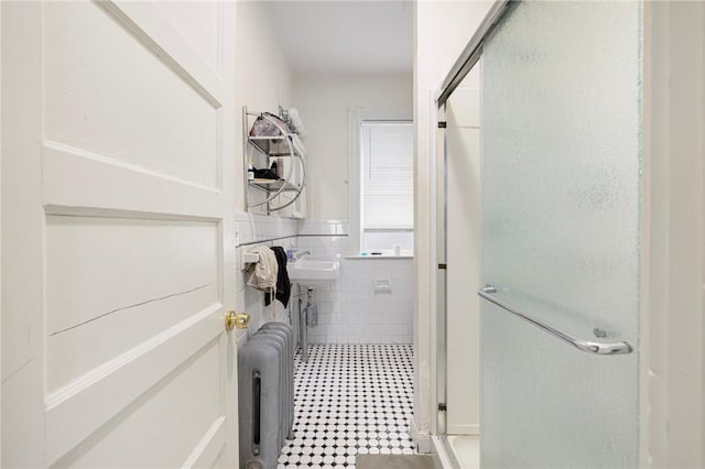 bathroom featuring a shower stall, tile walls, radiator, and wainscoting