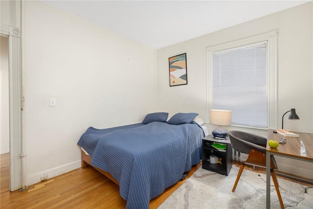 bedroom featuring wood finished floors, baseboards, and an office area