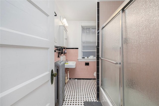 full bathroom with tile walls, an enclosed shower, toilet, wainscoting, and radiator