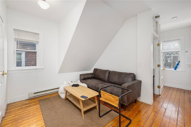 living area with a baseboard heating unit, light wood-style floors, and baseboards
