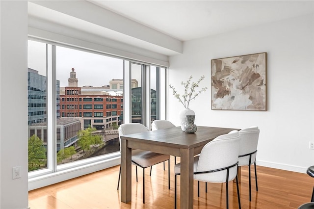 dining room with wood finished floors, baseboards, and a city view