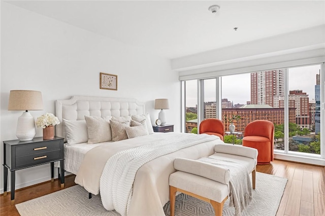 bedroom featuring wood finished floors and a city view
