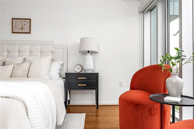 bedroom with wood finished floors, baseboards, and multiple windows