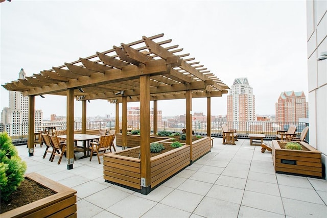 view of patio with a city view, a pergola, a garden, and outdoor dining space