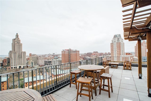 balcony with a city view, outdoor dining area, and a pergola
