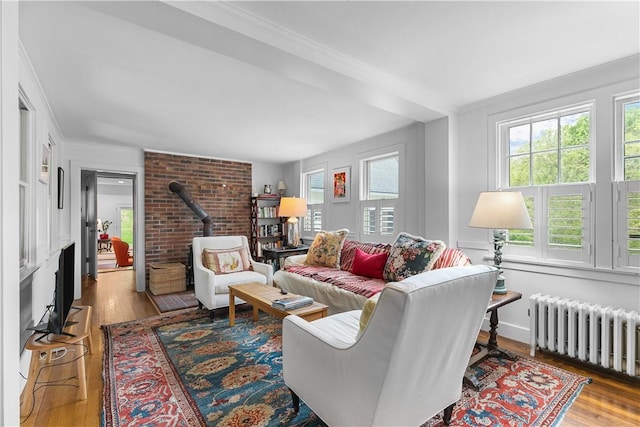 8001 Post Rd, North Kingstown, RI 02852 - living area featuring radiator heating unit, healthy amount of natural light, a wood stove, ornamental molding, and wood finished floors