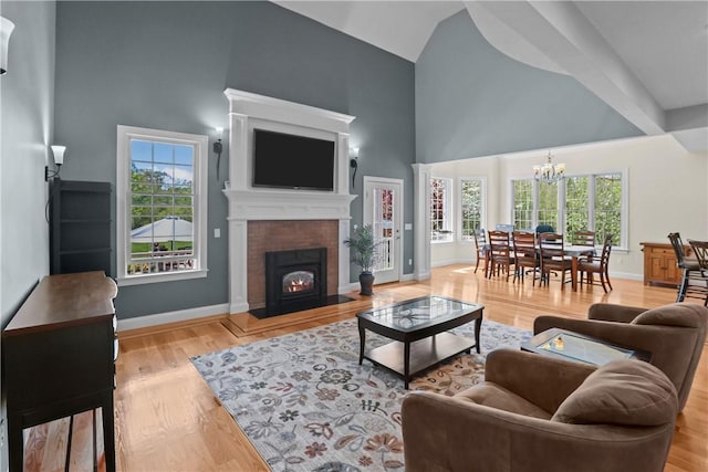 115 Read St, Attleboro, MA 02703 - living area featuring high vaulted ceiling, a chandelier, light wood-style floors, a warm lit fireplace, and baseboards