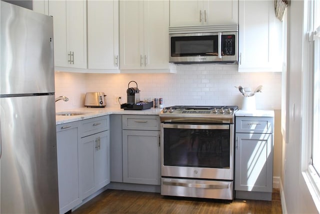 44 Bay St Unit B110, Westerly, RI 02891 - kitchen featuring appliances with stainless steel finishes, gray cabinets, a sink, dark wood-style flooring, and decorative backsplash