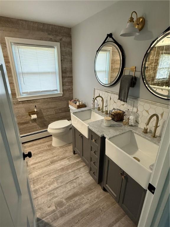 446 Angell Rd, North Providence, RI 02904 - bathroom with a baseboard radiator, wood finished floors, double vanity, toilet, and tasteful backsplash
