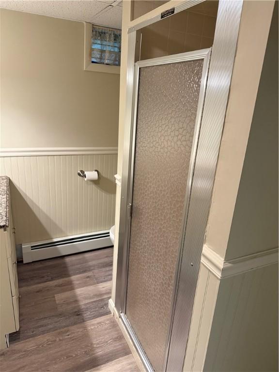 446 Angell Rd, North Providence, RI 02904 - full bathroom with baseboard heating, wainscoting, a shower stall, wood finished floors, and toilet