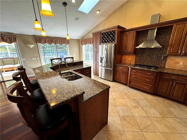 kitchen with appliances with stainless steel finishes, a sink, a skylight, backsplash, and vaulted ceiling