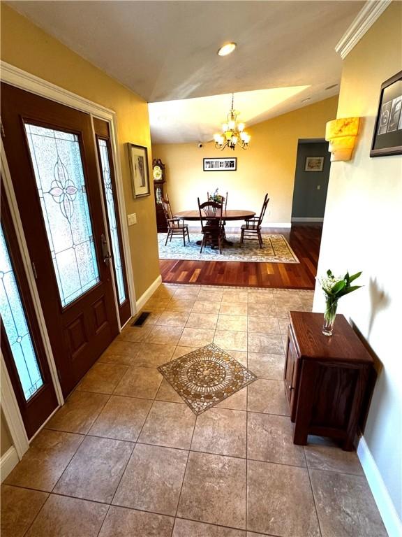 tiled foyer entrance featuring a chandelier, baseboards, and recessed lighting