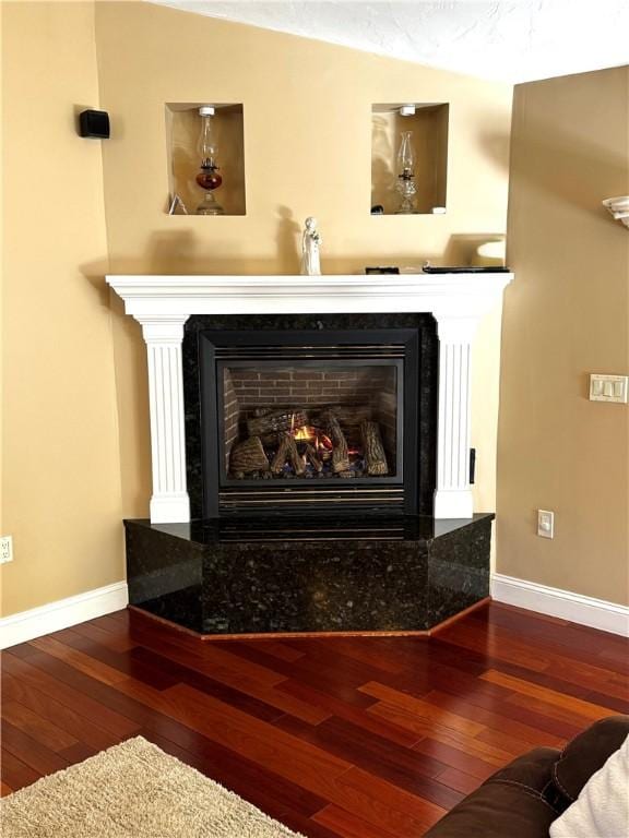 detailed view of a fireplace, baseboards, and wood finished floors