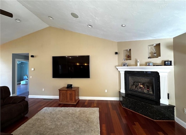 living room with wood finished floors, vaulted ceiling, baseboards, a glass covered fireplace, and recessed lighting