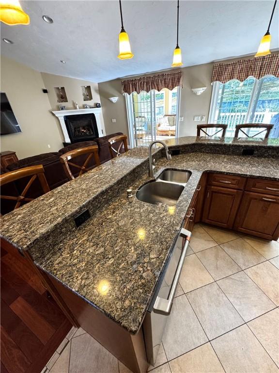 kitchen featuring a sink, light tile patterned floors, open floor plan, pendant lighting, and plenty of natural light