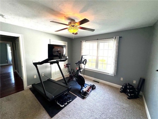 workout room with carpet, a ceiling fan, baseboards, and a textured ceiling