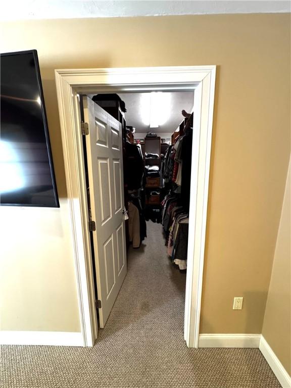 hall featuring carpet floors, baseboards, and a desk