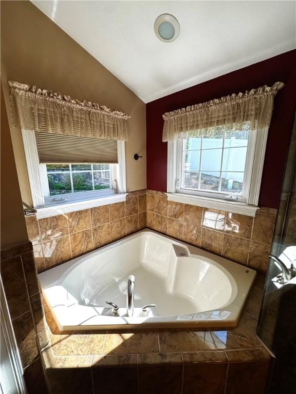 full bath with lofted ceiling, healthy amount of natural light, and a bath