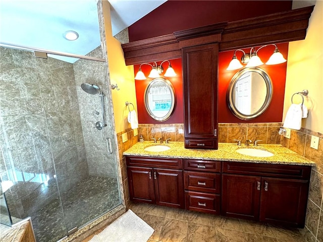 bathroom featuring a stall shower, double vanity, and tile walls