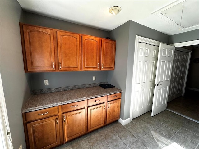 kitchen with brown cabinets, dark countertops, and light tile patterned floors