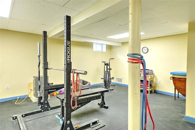 exercise room with a drop ceiling and baseboards