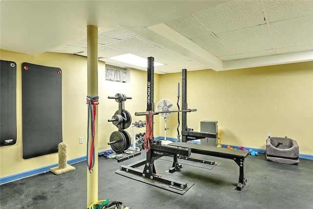 workout room featuring a drop ceiling and baseboards