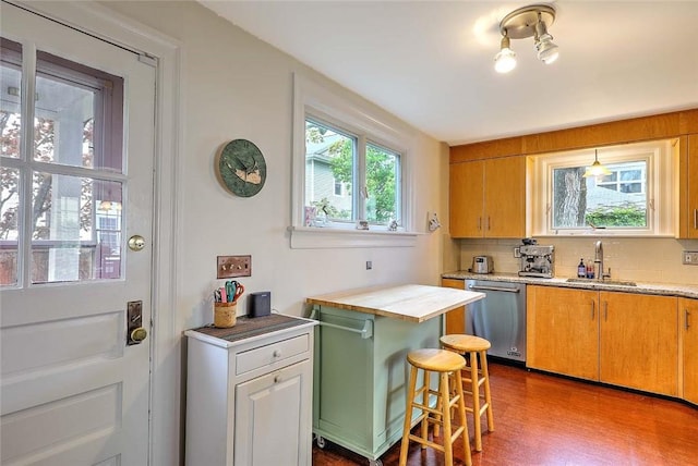kitchen with dishwasher, a sink, light countertops, decorative backsplash, and a kitchen breakfast bar