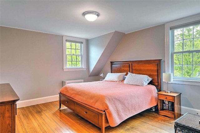 bedroom featuring baseboards, hardwood / wood-style floors, and multiple windows