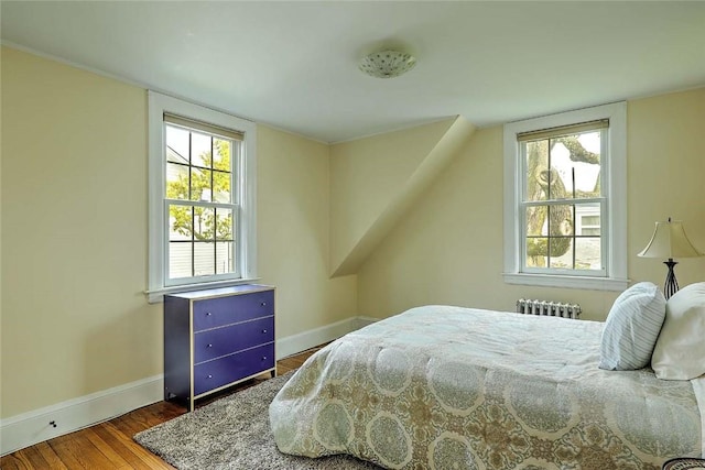 bedroom featuring radiator, baseboards, and wood finished floors
