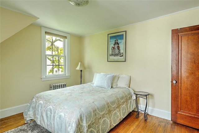 bedroom with radiator heating unit, baseboards, hardwood / wood-style floors, and crown molding