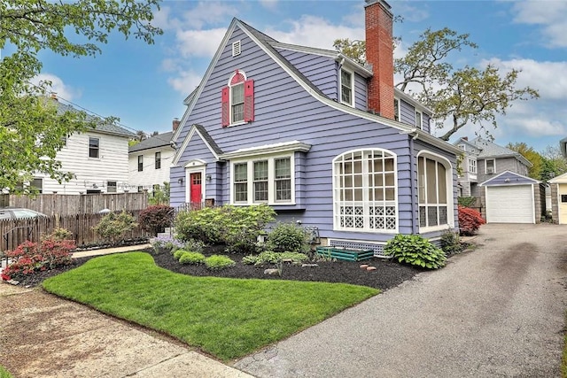 view of front of home with a chimney, an outdoor structure, a detached garage, and asphalt driveway