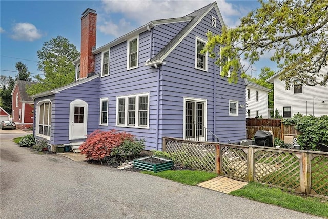 back of house with a chimney, fence, and entry steps