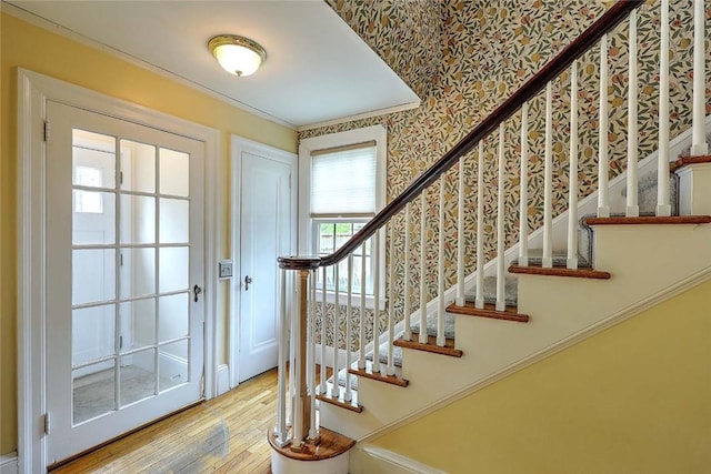 foyer entrance with hardwood / wood-style floors, stairs, wallpapered walls, and ornamental molding