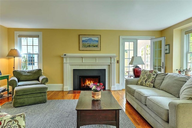living room with a brick fireplace, wood finished floors, and baseboards