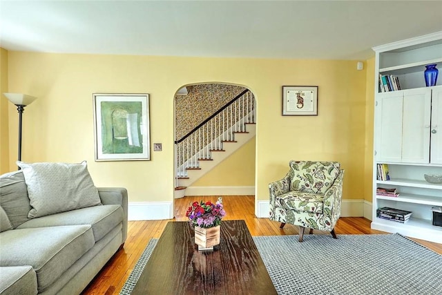 living area with stairway, baseboards, and wood finished floors