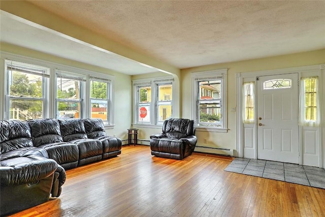 living area with a baseboard heating unit, hardwood / wood-style flooring, and a textured ceiling