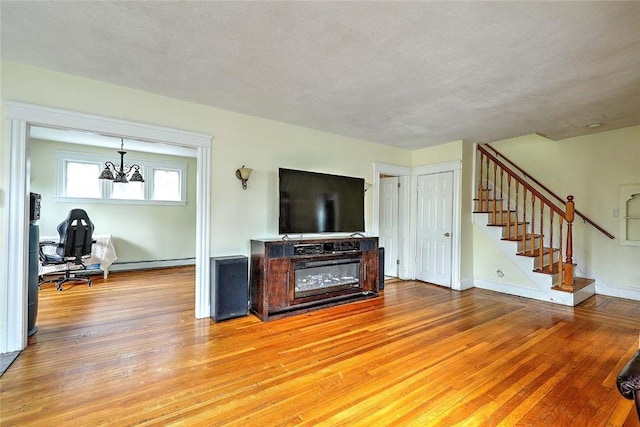 living room featuring light wood-type flooring, stairway, baseboards, a chandelier, and a desk