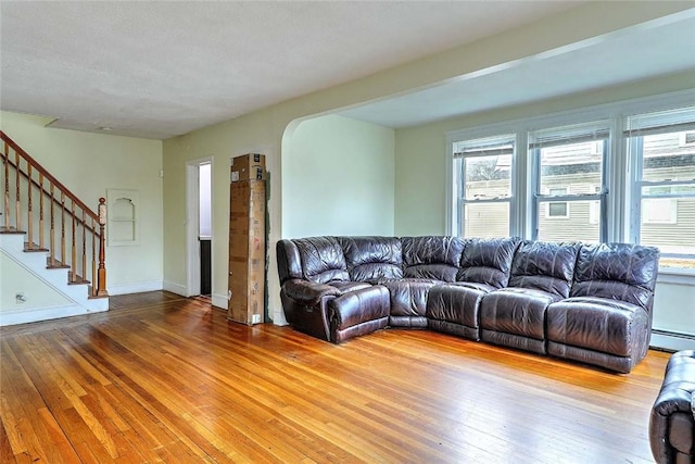 living room with plenty of natural light, light wood finished floors, stairway, and a baseboard radiator