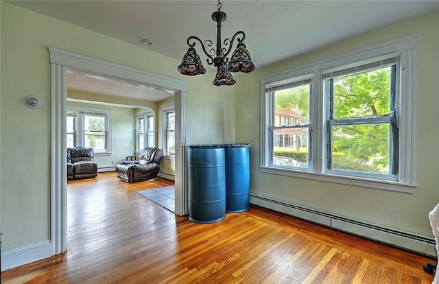dining area with baseboard heating, wood finished floors, a baseboard radiator, and a chandelier