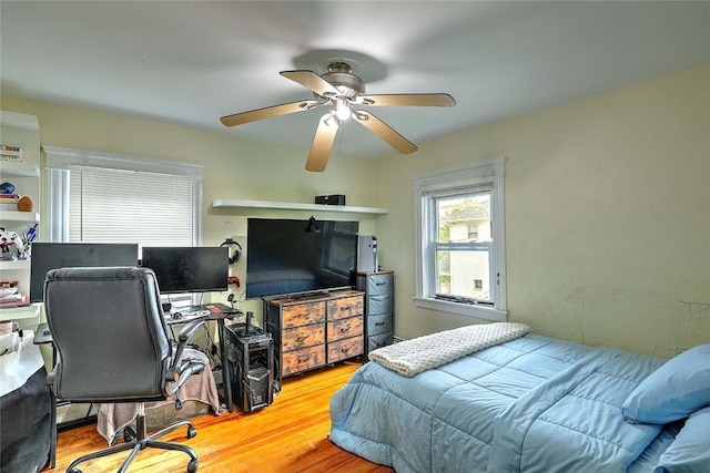 bedroom featuring wood finished floors, an office area, and a ceiling fan