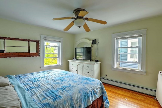 bedroom with a baseboard radiator, light wood-style floors, and ceiling fan