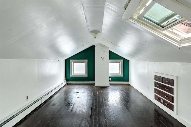 additional living space with a baseboard heating unit, a skylight, hardwood / wood-style floors, vaulted ceiling, and baseboards