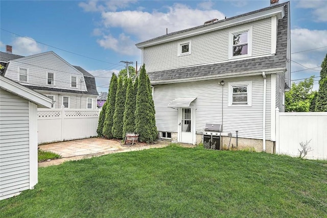 back of property with roof with shingles, a chimney, and a patio area