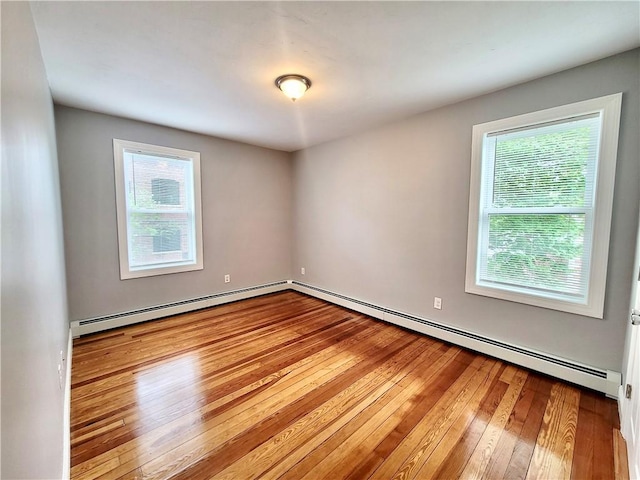 empty room featuring baseboard heating and hardwood / wood-style flooring