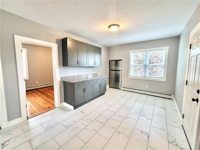 kitchen featuring a baseboard radiator, light marble finish floors, and freestanding refrigerator