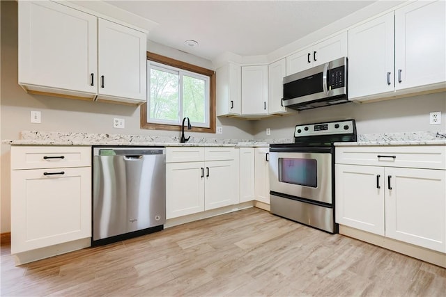 274 Courthouse Ln, Burrillville, RI 02859 - kitchen with appliances with stainless steel finishes, light wood finished floors, white cabinetry, and light stone countertops