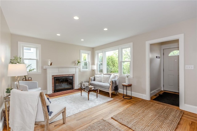living room with healthy amount of natural light, a brick fireplace, baseboards, wood finished floors, and recessed lighting