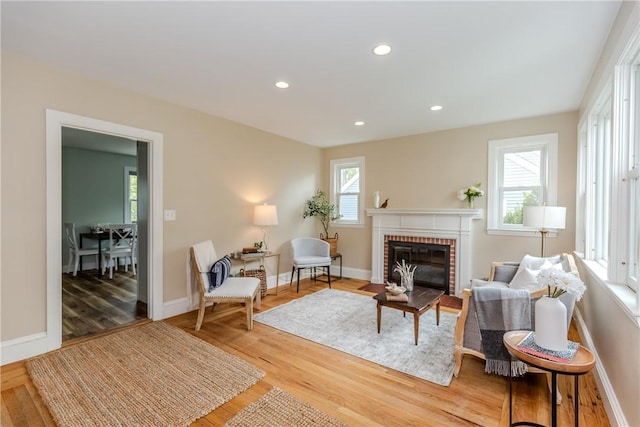 sitting room with plenty of natural light, a brick fireplace, wood finished floors, and recessed lighting